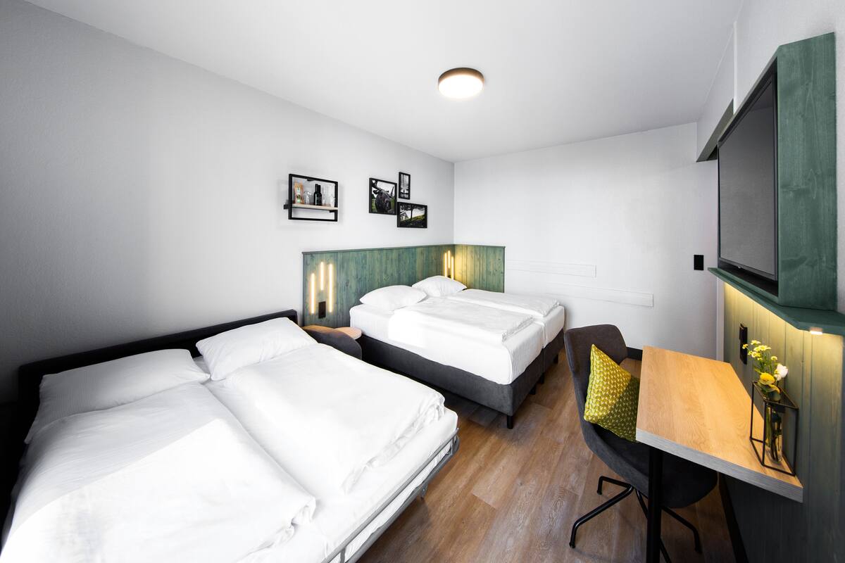 Una habitación de hotel moderna con dos camas, un escritorio y una televisión.