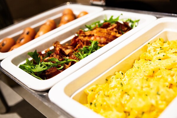 A buffet with various dishes including greens, meat, and potatoes.
