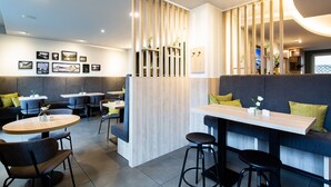 Un restaurante moderno con un separador de madera, asientos acolchados y varias fotografías enmarcadas en las paredes.