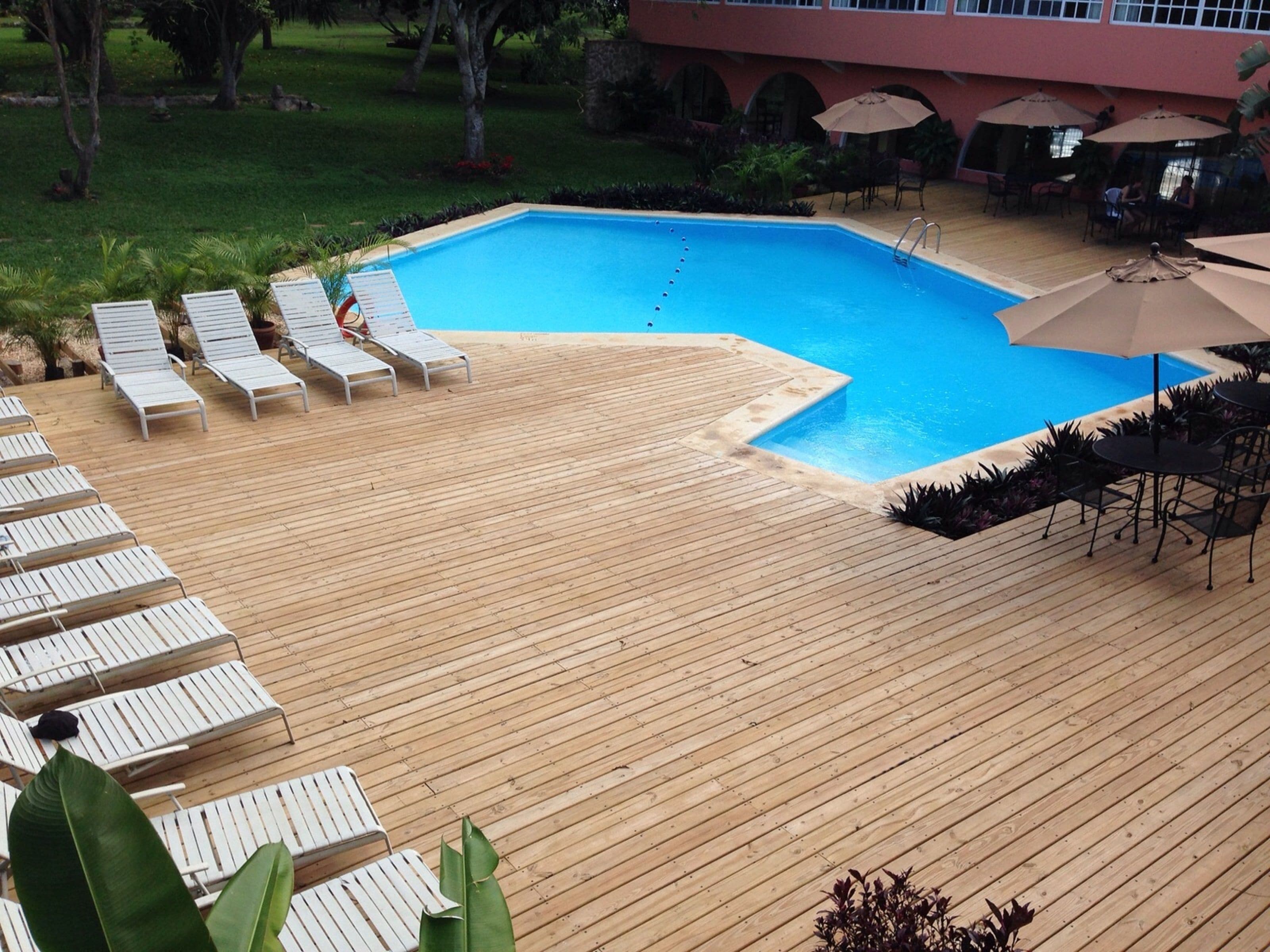 Una terraza de madera con sillones de descanso y una piscina.