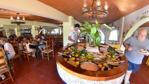 Una mesa de buffet con diversos alimentos y personal de servicio.
