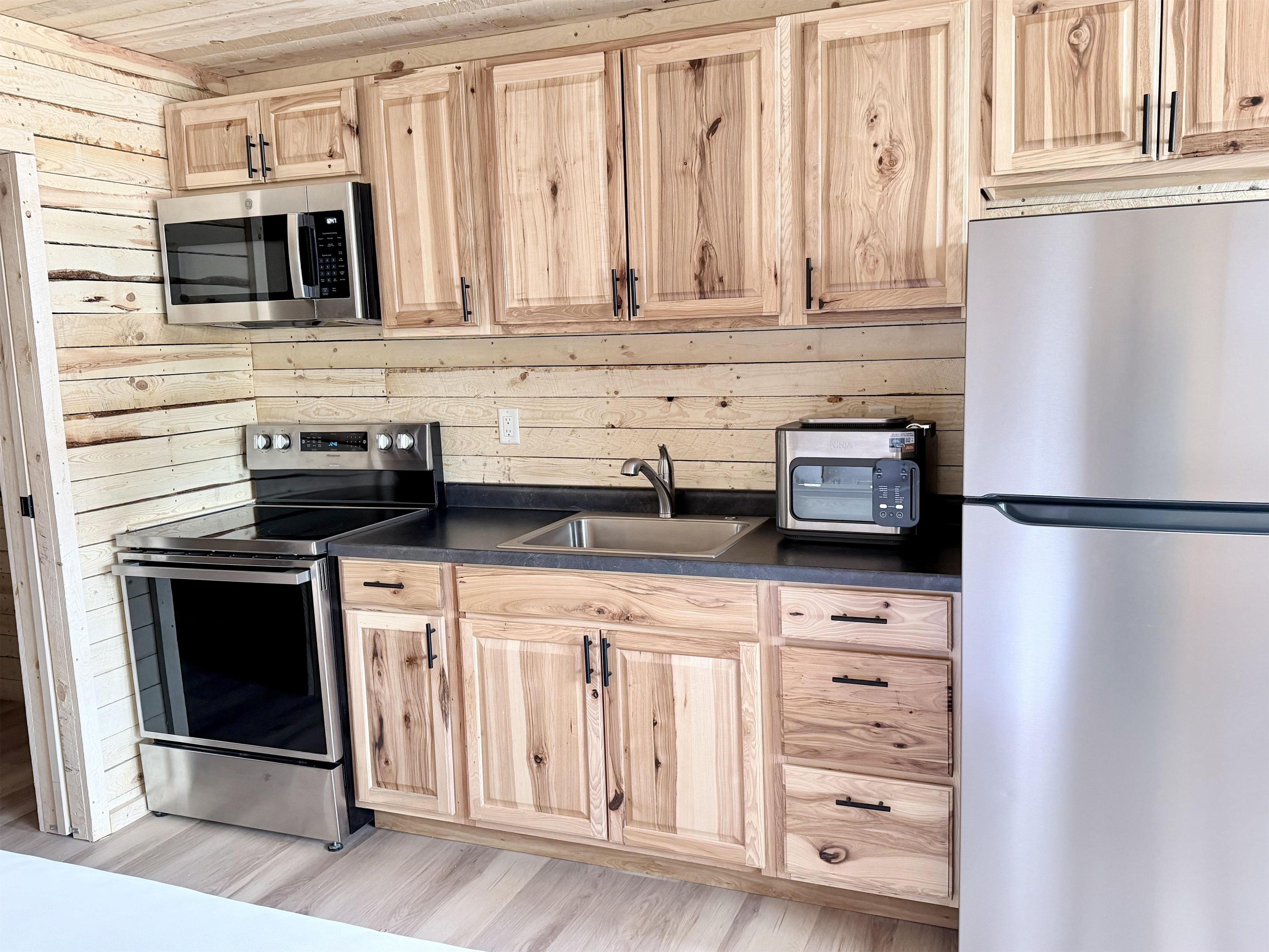 A kitchen with wooden cabinetry, stainless steel appliances, and a built-in microwave.