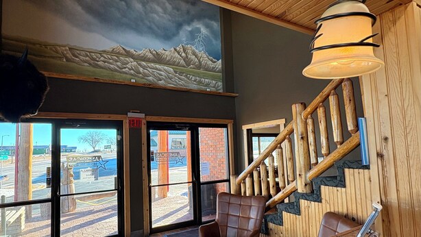 A room with a view of a mountain range through large windows, a wooden staircase, and a brown leather chair. - Americas Best Value Inn Wall (Wall)