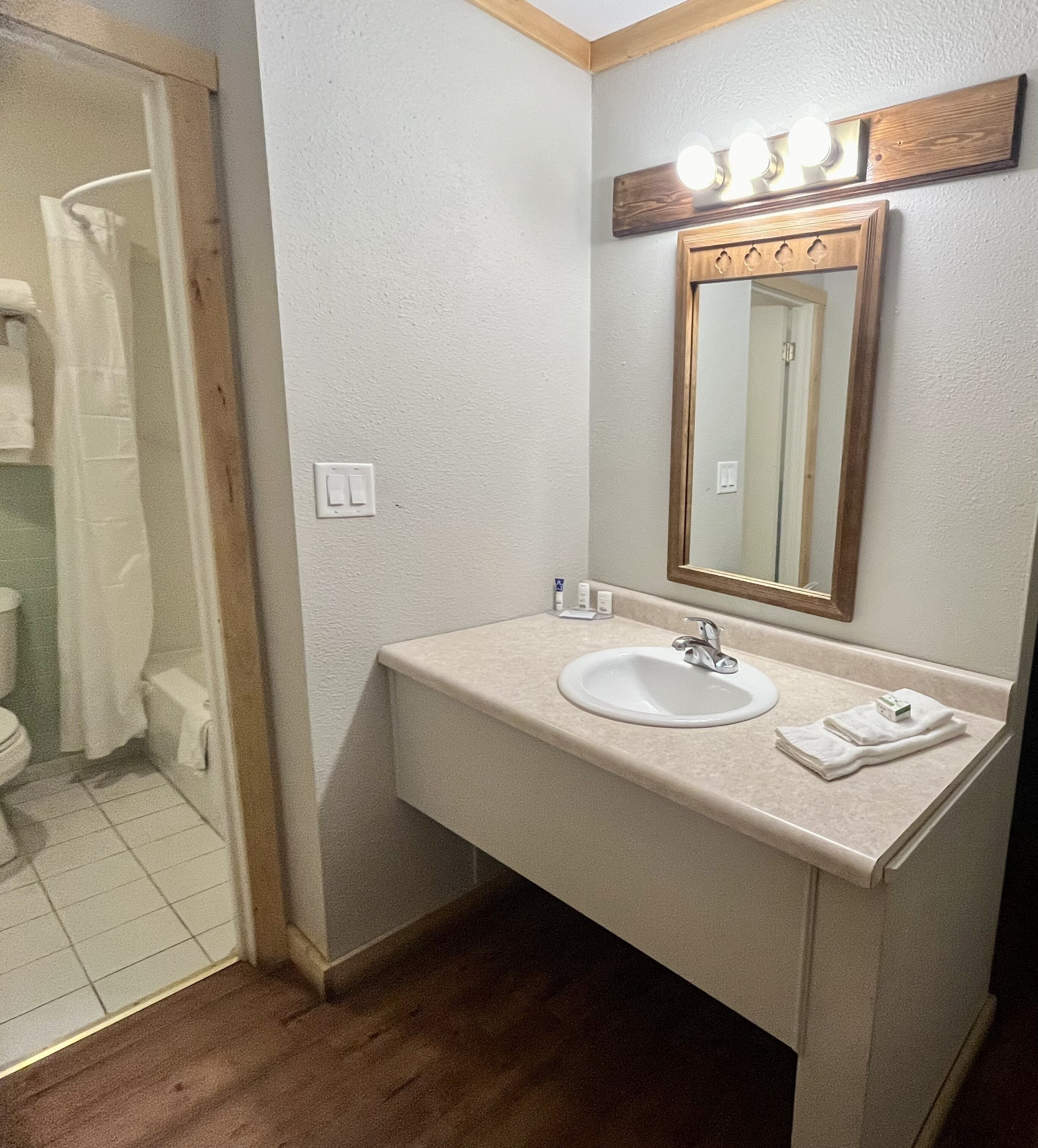 A bathroom with a sink, mirror, and lights above the mirror.