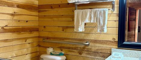 A wooden-paneled bathroom with a toilet, a sink, and a towel rack.