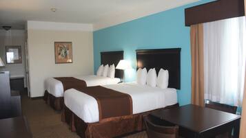 A hotel room with two beds, a desk, and a chair.