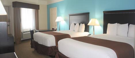 A hotel room with two beds, a desk, and a chair.
