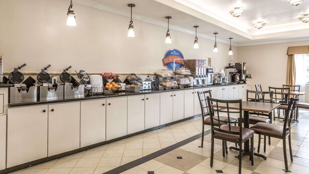 Una barra de desayuno con máquinas para hacer gofres, cafeteras y un cartel que indica la zona de desayuno.