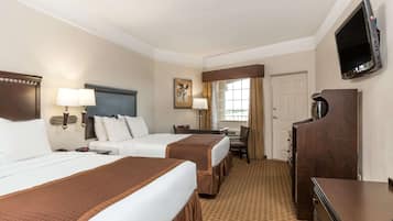 Une chambre d’hôtel avec deux lits, un bureau, une chaise, une télévision et une armoire.
