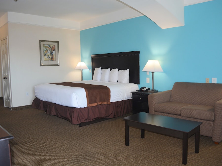 A hotel room with a bed, a desk, a chair, and a lamp.