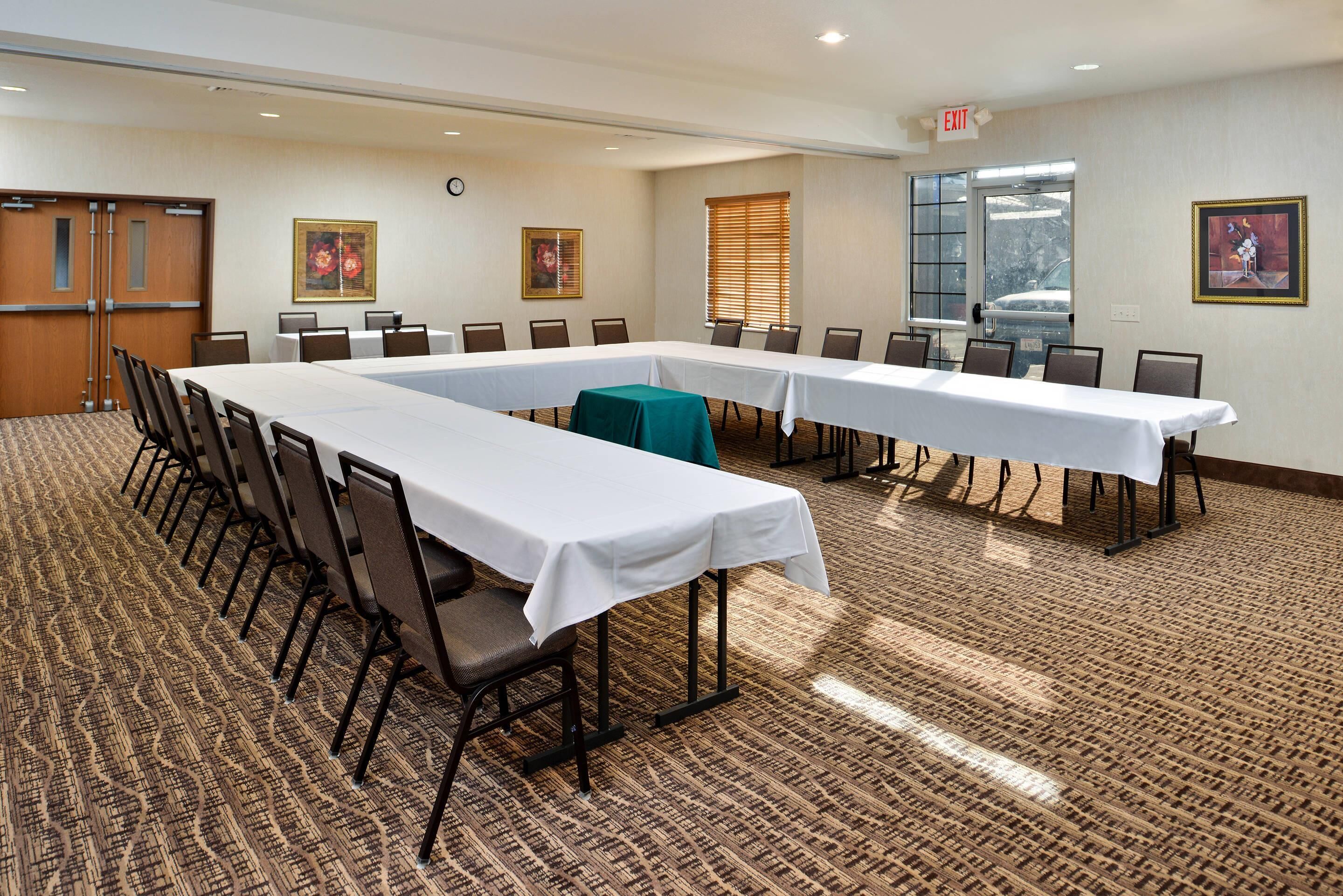 A conference room with long tables, chairs, and a carpeted floor.