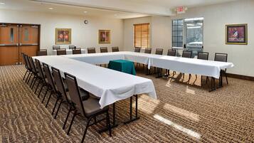 A conference room with long tables, chairs, and a carpeted floor.