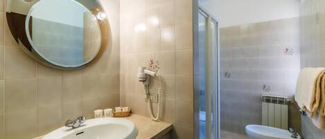 A bathroom with a round mirror, a sink, a toilet, and a shower area.