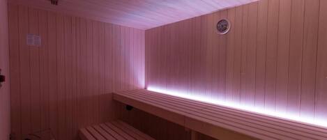 A wooden sauna with benches and a wall-mounted heater.