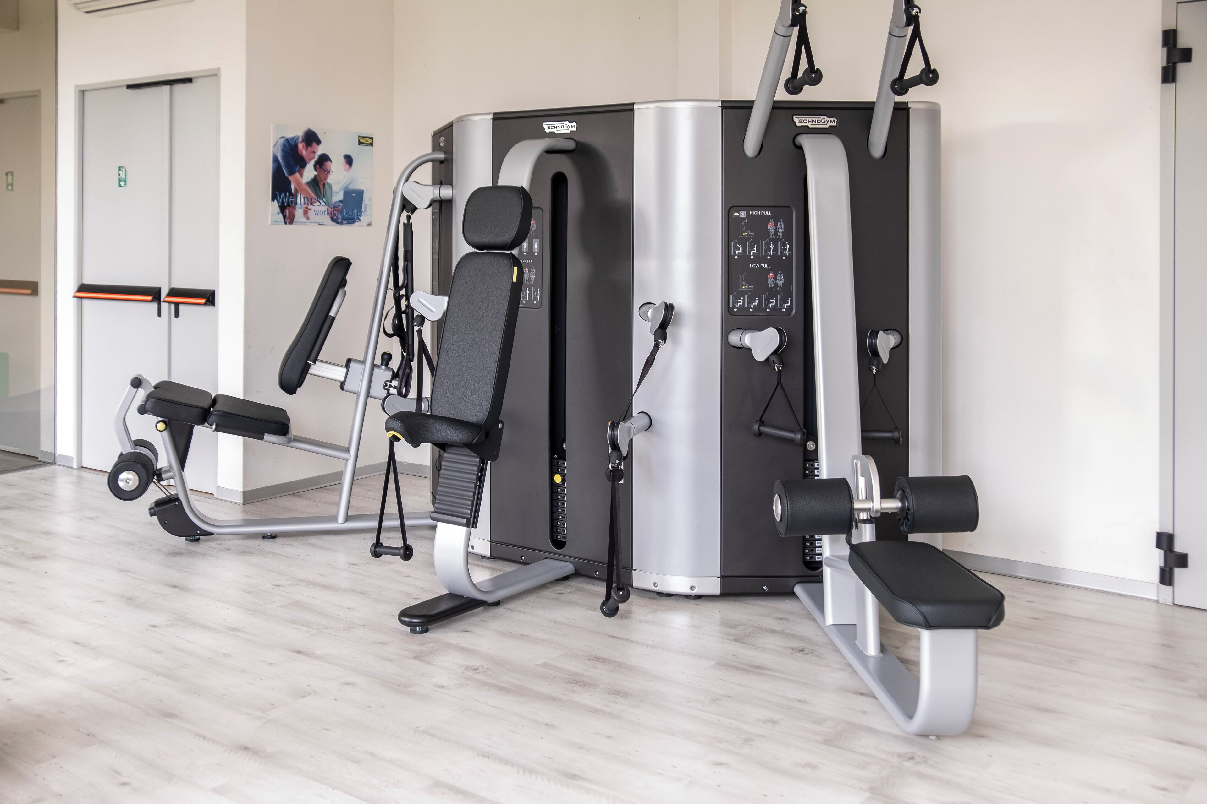 Un gimnasio con equipo de ejercicio, incluyendo una banca, una máquina de pesas y una máquina de poleas.