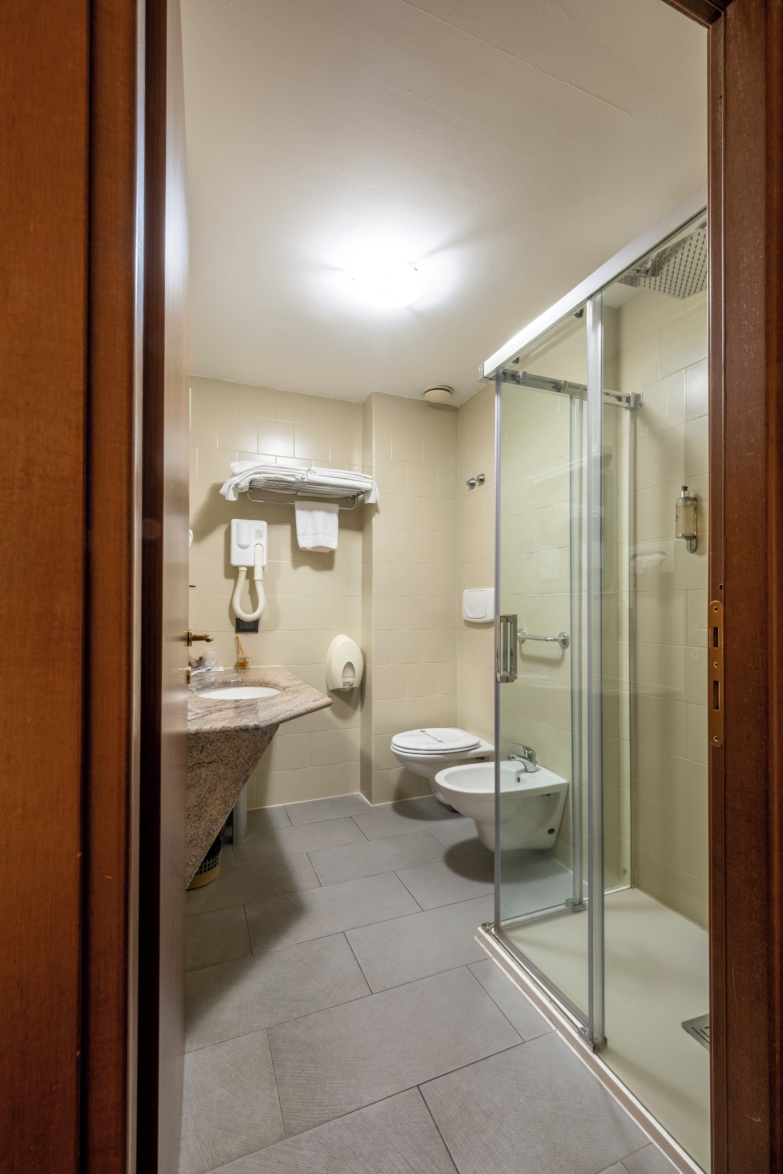 Ein modernes Badezimmer mit einer gläsernen Duschkabine, einem Waschbecken mit Marmorplatte und einer Toilette.