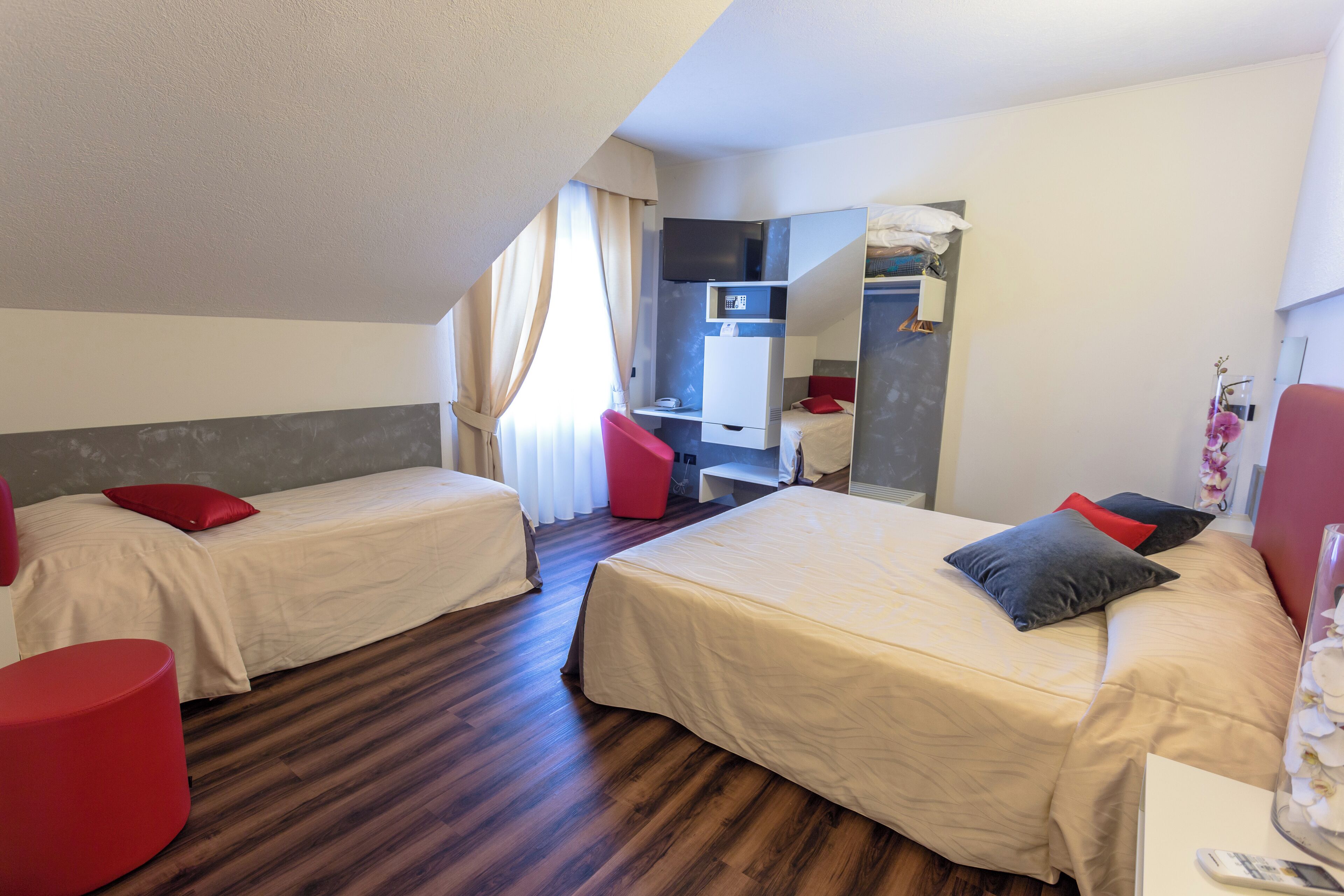 Habitación de hotel con dos camas, un escritorio, una silla y un espejo.