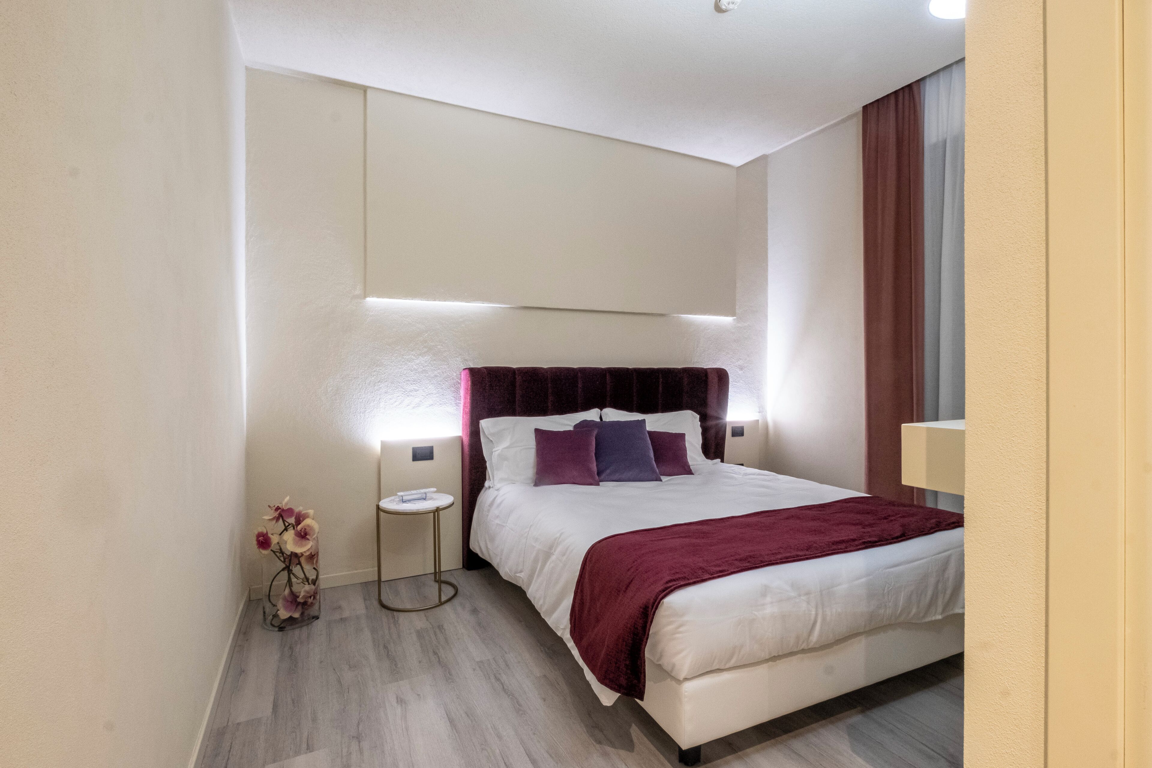 Una habitación de hotel moderna con una cama grande, una mesita de noche y una pequeña mesa auxiliar.