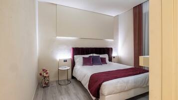 A modern hotel room with a large bed, a bedside table, and a small side table.