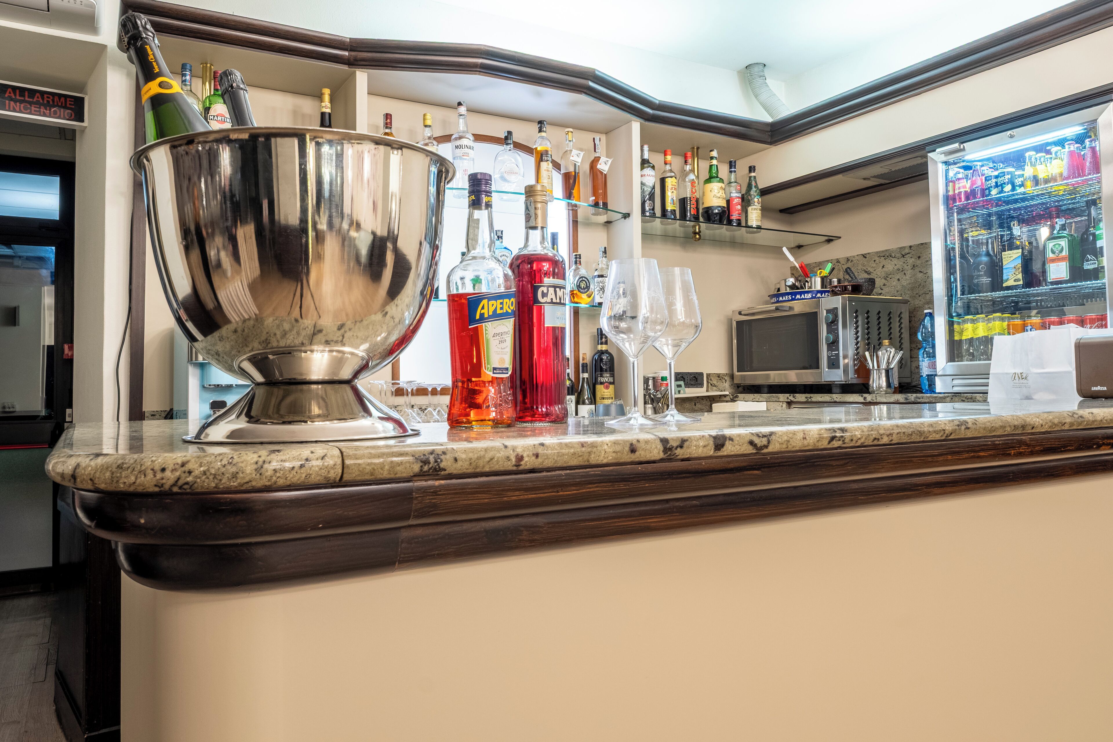 A bar area with a large metal bowl, bottles of liquor, and wine glasses.