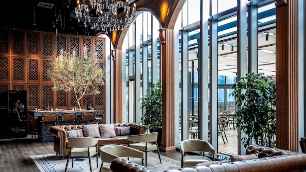 Un amplio salón con sofás de cuero, una mesa de comedor y una araña.