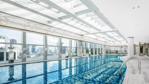 Una piscina interior moderna con vistas a la ciudad, grandes ventanales y tragaluces.