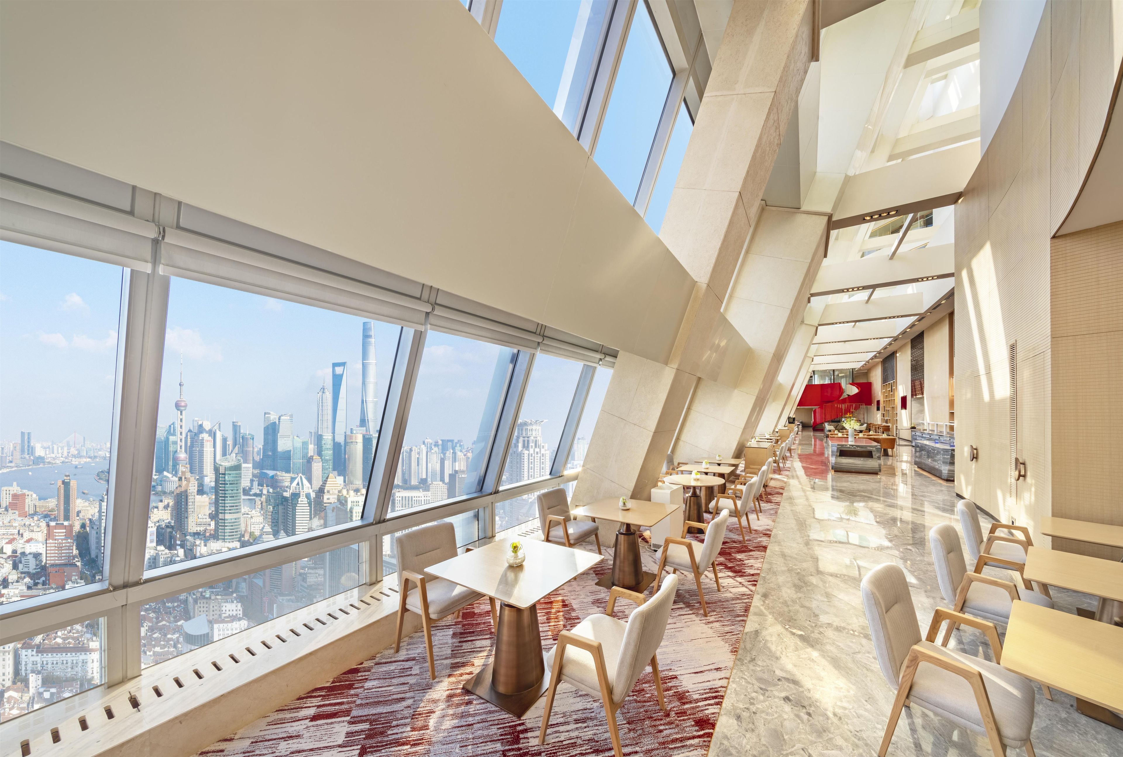A modern hotel interior with a dining area, large windows, and a city view.