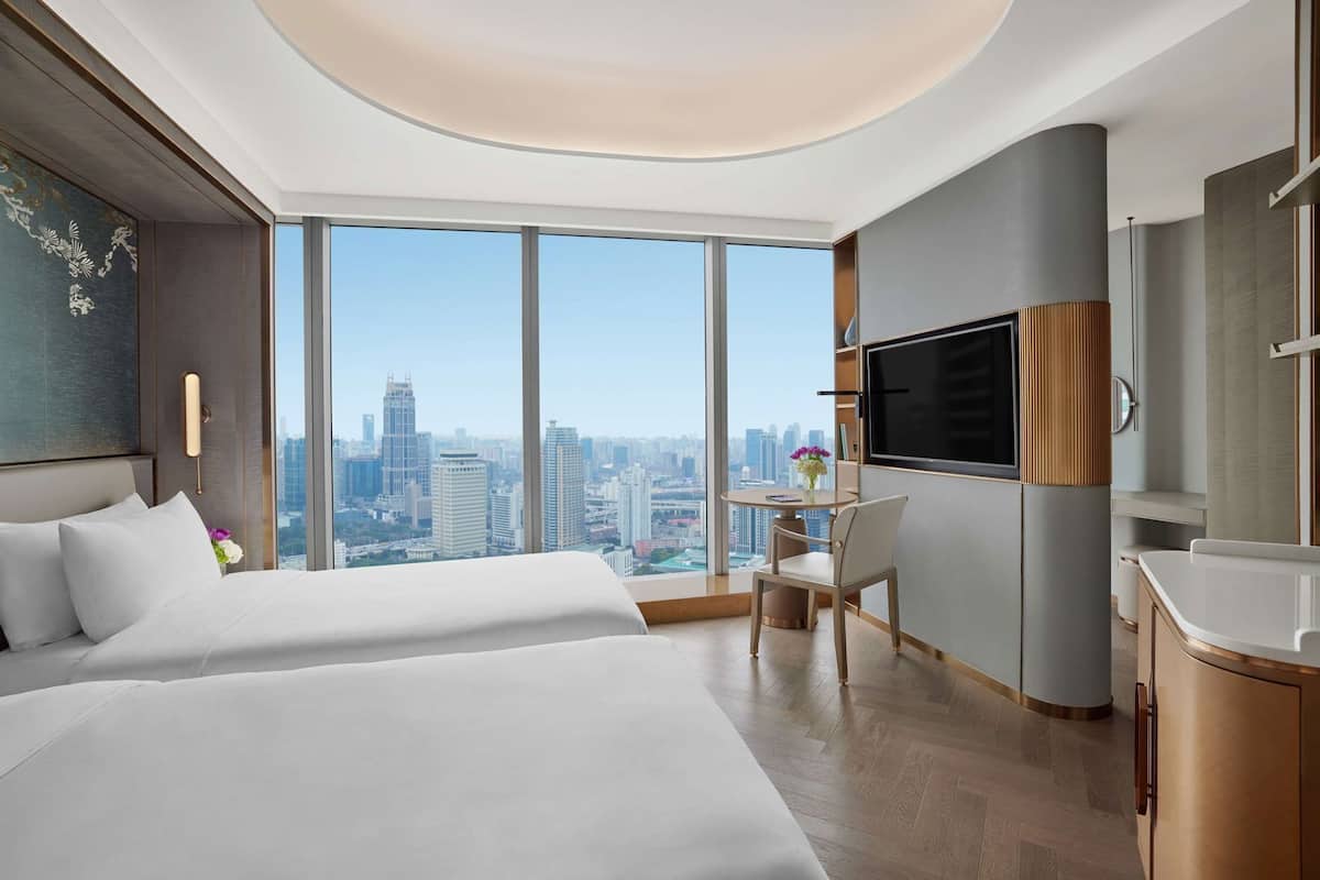 Una habitación de hotel moderna con una cama grande, un escritorio, un televisor y vistas a la ciudad.