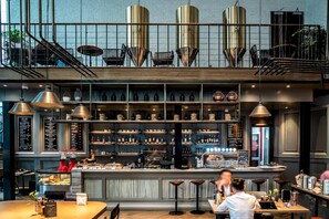 A bar area with a counter, shelves with bottles, and stools.
