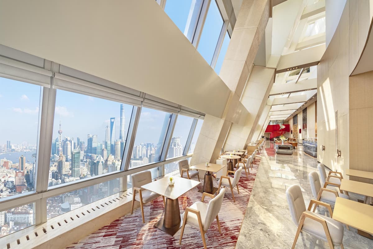 Interior de un hotel de gran altura con vistas panorámicas de la ciudad, muebles modernos y un diseño espacioso.