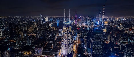 A nighttime cityscape with illuminated skyscrapers and a river.