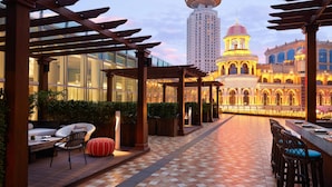 Terraza en la azotea con una pérgola, zona de estar y vista a un edificio histórico con torre.