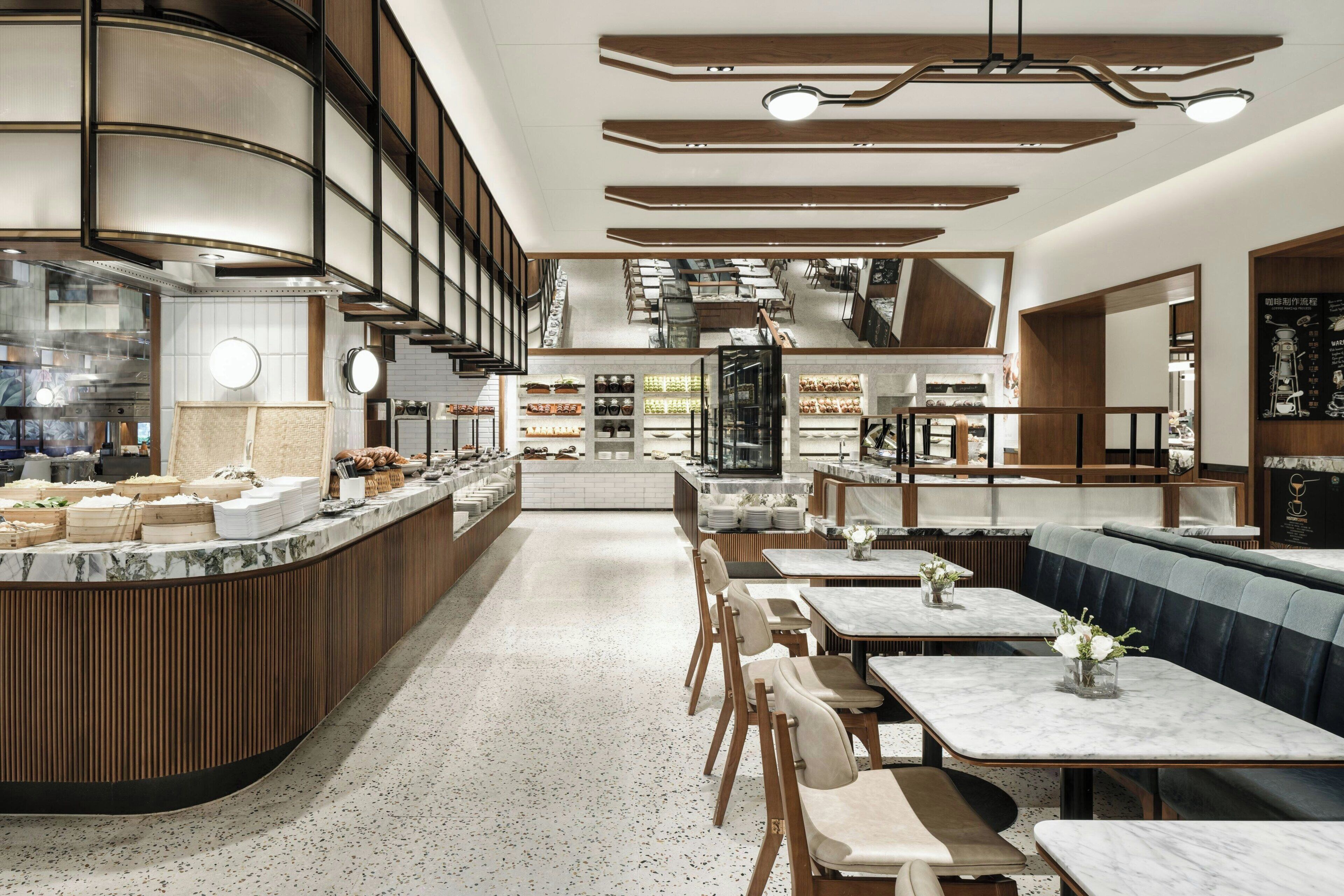 A modern restaurant interior with a counter, seating area, and kitchen in the background.