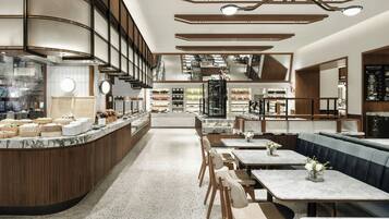 A modern restaurant interior with a counter, seating area, and kitchen in the background.