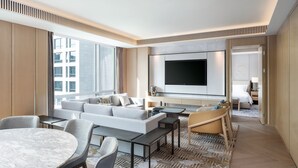 Une chambre d’hôtel moderne dotée d’un grand téléviseur à écran plat, d’un canapé, d’une table à manger et d’un tapis à motifs.