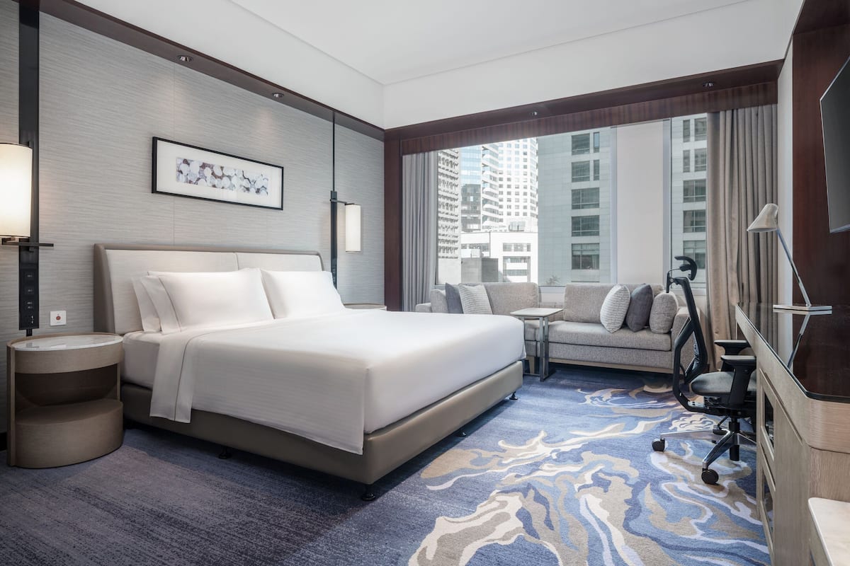 A hotel room with a large bed, a sofa, a small table, and a TV.