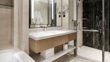 A modern bathroom with a large mirror, two sinks, a shower, and a bathtub.