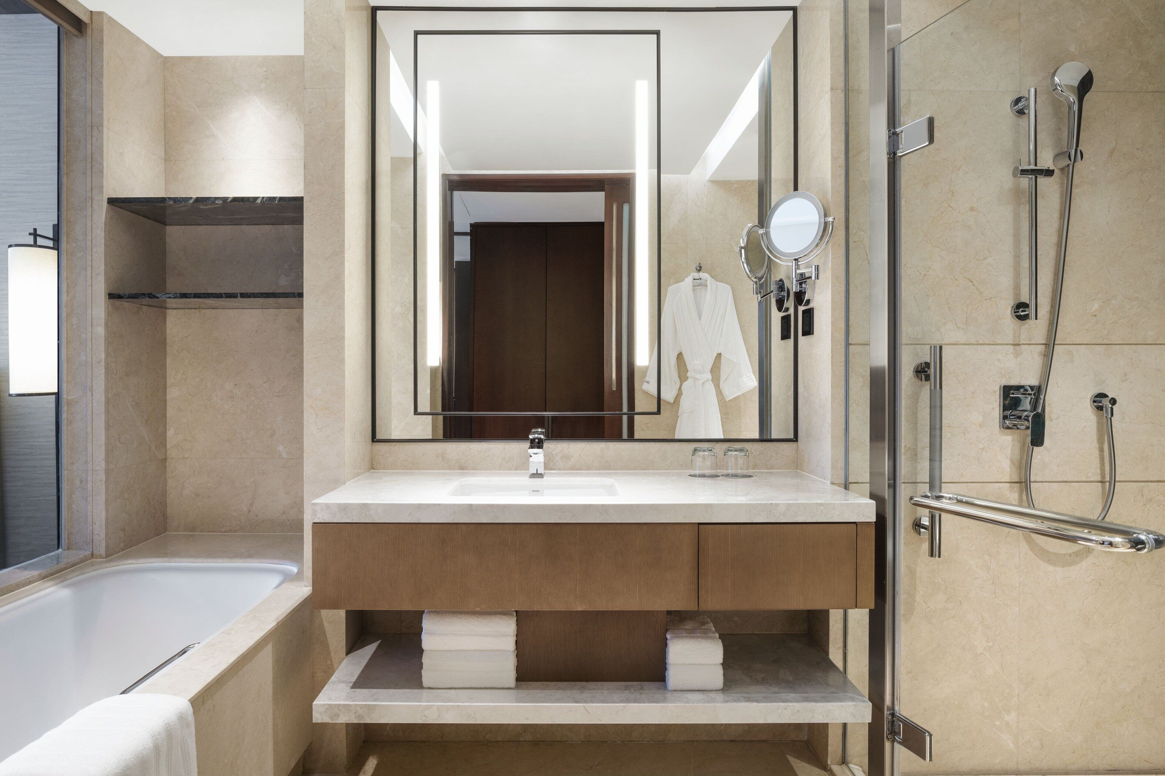 Un baño moderno con bañera, un espejo grande, un tocador con lavabo y una zona de ducha.