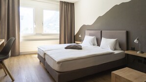 Ein ordentlich eingerichtetes Schlafzimmer mit einem großen Bett, einem Schreibtisch und einem Stuhl.