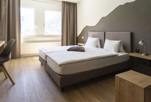 Un dormitorio ordenado con una cama grande, un escritorio y una silla.
