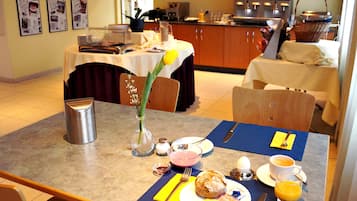 A breakfast setting with a table set for two, including plates with food, a coffee cup, and a glass of orange juice.