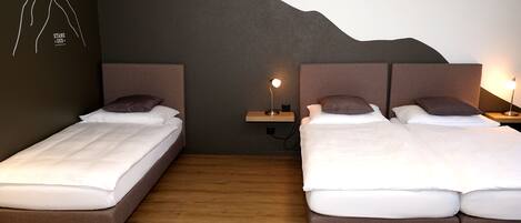 Habitación de hotel con dos camas, piso de madera y una pared con diseño de montaña.
