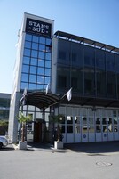 Un hotel moderno con fachada de vidrio, un letrero llamativo que dice "STANS SUD HOTEL" y un área de entrada cubierta.