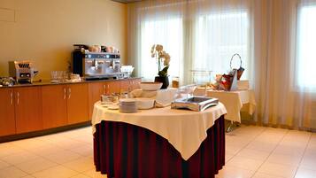Ein Hotel-Speisebereich mit einem reichhaltigen Buffet, darunter eine Kaffeestation und ein Tisch mit rotem Tischtuch.