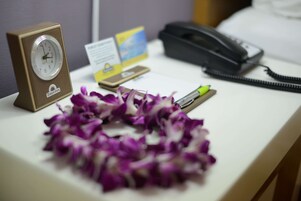 A desk with a clock, a phone, a card, and a pen.