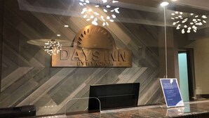 A reception desk with a sign reading "DAY'S INN BY WYNDHAM" and a "Tips for a safer stay" sign. - Days Inn Guam-Tamuning (Tamuning)