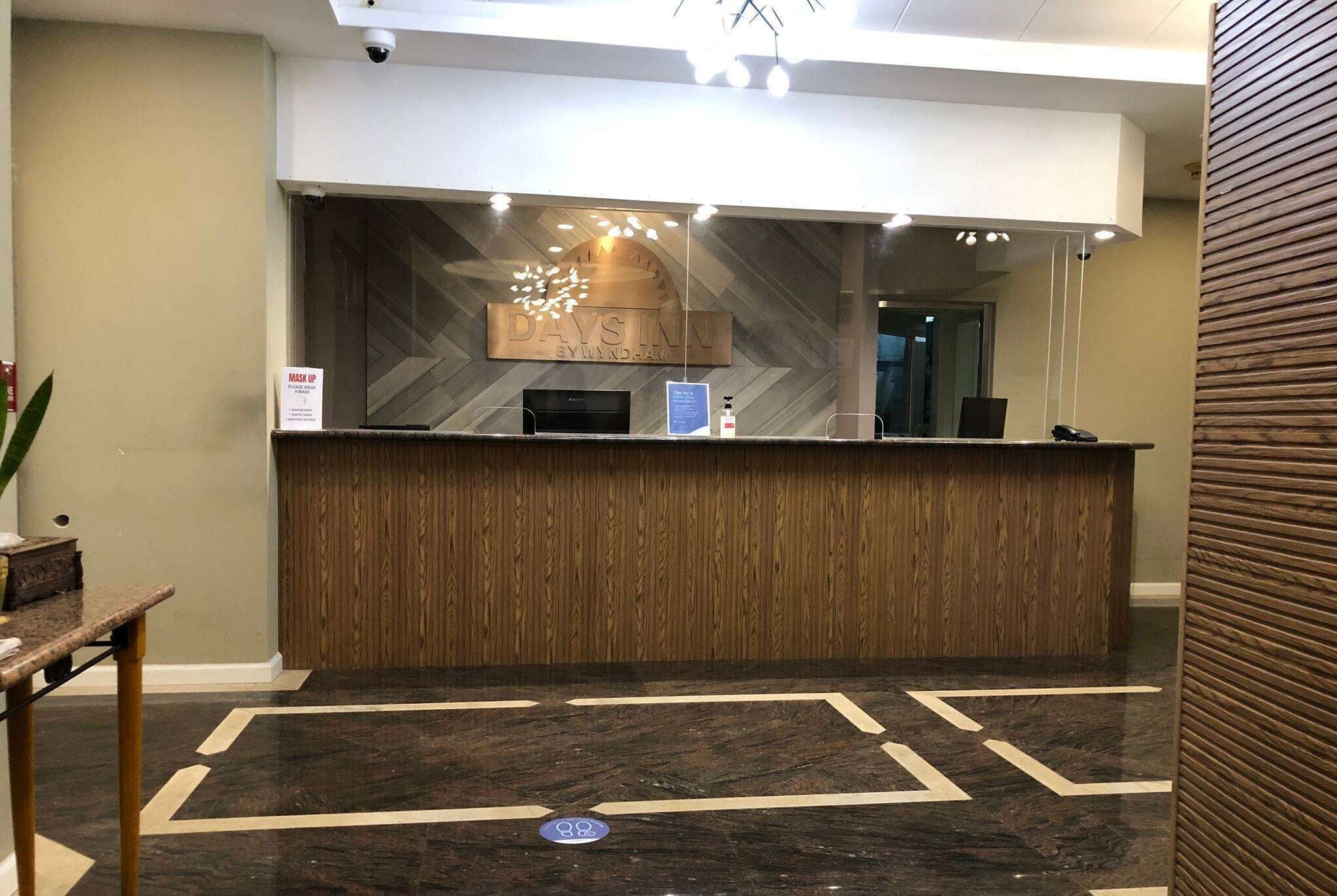 Un área de recepción con un mostrador de madera, un cartel encima y un piso con diseño.