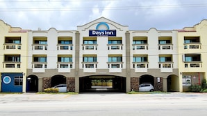 A multi-story hotel with a central entrance, balconies, and a sign for Days Inn. - Days Inn Guam-Tamuning (Tamuning)