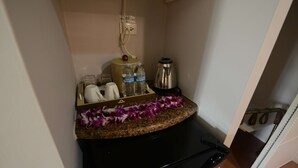 A kitchen with a granite countertop, a coffee maker, two water bottles, a kettle, and a trash bin. - Days Inn Guam-Tamuning (Tamuning)