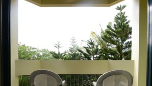 A balcony with two wicker chairs and a small table, surrounded by a tiled floor and a railing. - Days Inn Guam-Tamuning (Tamuning)